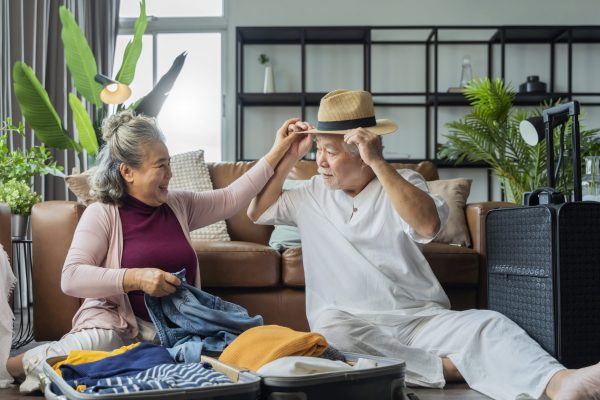 old asian senior couple packing cloth and stuff for a trip together,happiness asian old age retired mature adult enjoy arrange cloth together on floor at living room at home interior background